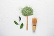 Heap of powdered matcha tea, spoon and chasen on light background