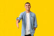 Handsome young man extending hand for handshake on yellow background