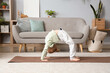 Cute little girl practicing yoga on mat in living room