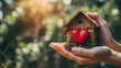 © Andrii Yalanskyi - Home sweet home concept. Dream housing. Real estate. Hands holding miniature house with a red heart outdoors on a sunny summer day