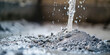 Water Mixing with Cement Powder. A close-up shot of water splashing onto dry cement powder, depicting the initial stage of mixing construction material, copy space.