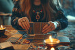  Woman's hands with magic rings holding cards for fortune telling. Fortune teller at table, front view. Candles are burning.