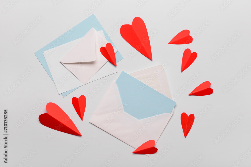 Envelopes with blank cards and red paper hearts on white background. Valentine's Day celebration