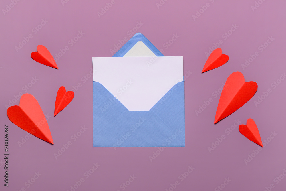 Envelope with blank card and red paper hearts on lilac background. Valentine's Day celebration