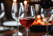 Red Wine Being Poured Into A Glass With Grapes In The Background.