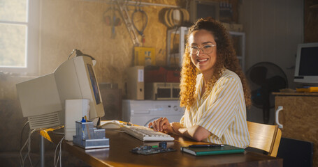 Fototapete - Hispanic Female Software Engineer Programming On Old Desktop Computer In Retro Garage, Looking At Camera And Smiling. Woman Starting an Innovative Startup Company In Nineties. Nostalgia Concept.