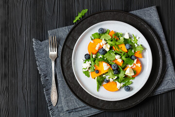 Wall Mural - arugula persimmon cheese berries salad, top view