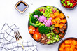Vegan buddha bowl with pumpkin, quinoa, tomatoes, spinach, celery, edamame, tofu, cauliflower, broccoli and sesame seeds, white table background, top view. Healthy vegetarian comfort food