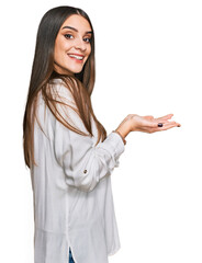 Wall Mural - Young beautiful woman wearing casual white shirt pointing aside with hands open palms showing copy space, presenting advertisement smiling excited happy