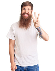 Poster - Handsome young red head man with long beard wearing casual white tshirt showing and pointing up with fingers number three while smiling confident and happy.