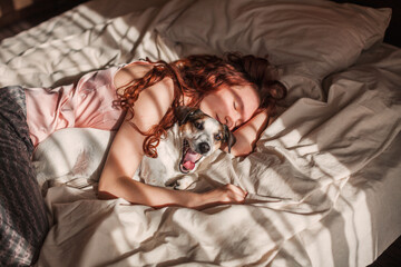 Wall Mural - Young woman sleeping with dog on bed