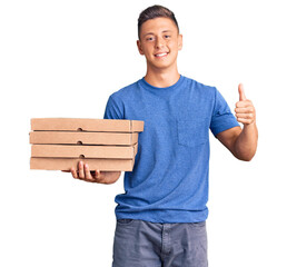 Poster - Young handsome hispanic man holding delivery pizza box smiling happy and positive, thumb up doing excellent and approval sign