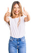 © Krakenimages.com - Beautiful caucasian woman with blonde hair wearing casual white tshirt approving doing positive gesture with hand, thumbs up smiling and happy for success. winner gesture.