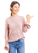 © Krakenimages.com - Beautiful caucasian woman with blonde hair wearing casual winter sweater smiling with happy face looking and pointing to the side with thumb up.
