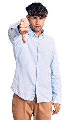 Sticker - Young hispanic man wearing casual shirt looking unhappy and angry showing rejection and negative with thumbs down gesture. bad expression.