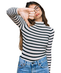 Sticker - Young beautiful teen girl wearing casual clothes and glasses looking unhappy and angry showing rejection and negative with thumbs down gesture. bad expression.