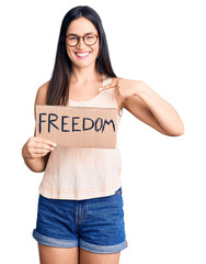 Canvas Print - Young beautiful caucasian woman holding freedom banner pointing finger to one self smiling happy and proud