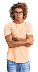 Sticker - Young hispanic man wearing casual clothes and glasses skeptic and nervous, disapproving expression on face with crossed arms. negative person.