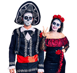 Canvas Print - Young couple wearing mexican day of the dead costume over background showing and pointing up with fingers number two while smiling confident and happy.