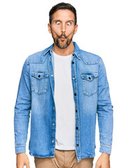 Wall Mural - Young handsome man wearing casual denim jacket making fish face with lips, crazy and comical gesture. funny expression.