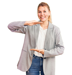 Wall Mural - Young beautiful blonde woman wearing elegant jacket gesturing with hands showing big and large size sign, measure symbol. smiling looking at the camera. measuring concept.