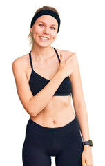 Wall Mural - Young beautiful blonde woman wearing sportswear cheerful with a smile of face pointing with hand and finger up to the side with happy and natural expression on face