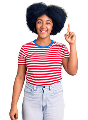 Canvas Print - Young african american girl wearing casual clothes pointing finger up with successful idea. exited and happy. number one.