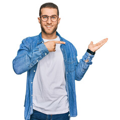 Canvas Print - Young caucasian man wearing casual clothes amazed and smiling to the camera while presenting with hand and pointing with finger.