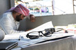 © Jack Tamrong - Closeup eyeglasses on paperwork with tired Arab worker man blurred background in workplace