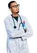 © Krakenimages.com - Young african american man wearing doctor uniform and stethoscope looking to the side with arms crossed convinced and confident