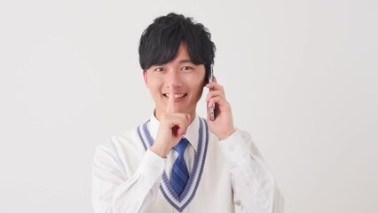 Sticker - スマートフォンで電話をしながら内緒のポーズをする男子高校生　白背景