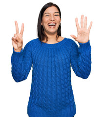 Wall Mural - Young hispanic woman wearing casual clothes showing and pointing up with fingers number seven while smiling confident and happy.