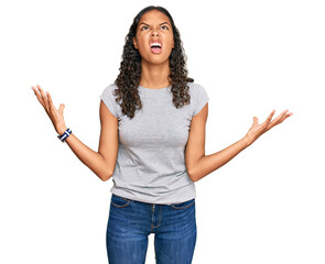 Wall Mural - Young african american girl wearing casual clothes crazy and mad shouting and yelling with aggressive expression and arms raised. frustration concept.