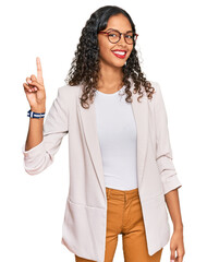 Wall Mural - Young african american girl wearing business clothes pointing finger up with successful idea. exited and happy. number one.