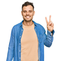 Sticker - Young hispanic man wearing casual clothes smiling with happy face winking at the camera doing victory sign. number two.