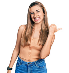 Sticker - Hispanic young woman wearing casual summer shirt smiling with happy face looking and pointing to the side with thumb up.