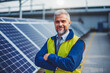 Director of factory standing by solar panels, representing renewable energy and corporate responsibility.