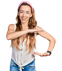 Canvas Print - Young caucasian woman wearing casual style with sleeveless shirt gesturing with hands showing big and large size sign, measure symbol. smiling looking at the camera. measuring concept.