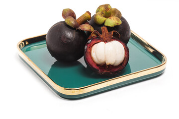 Half cut sliced and two whole fresh organic mangosteen delicious fruit in a green plate isolated on white background clipping path