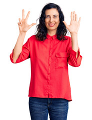 Sticker - Young beautiful hispanic woman wearing casual clothes showing and pointing up with fingers number eight while smiling confident and happy.