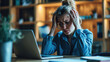 © Studio Nova - Woman feeling stressed while working on her laptop. She has her head in her hands, a pained expression on her face, signifying a headache, frustration, or exhaustion.