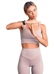 Wall Mural - Beautiful caucasian woman wearing sportswear doing time out gesture with hands, frustrated and serious face