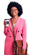 © Krakenimages.com - Young african american woman wearing leather bag and drinking a take away cup of coffee looking positive and happy standing and smiling with a confident smile showing teeth