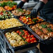A buffet worker at a hotel with a halal kitchen buffet wearing protective gloves prepares a variety of salads and side dishes, placing the ingredients in large black containers. Concept: catering 