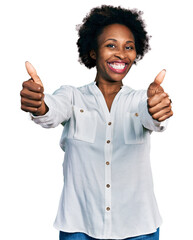 Poster - African american woman with afro hair wearing casual white t shirt approving doing positive gesture with hand, thumbs up smiling and happy for success. winner gesture.