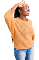 Wall Mural - Young african american woman wearing casual clothes very happy and smiling looking far away with hand over head. searching concept.