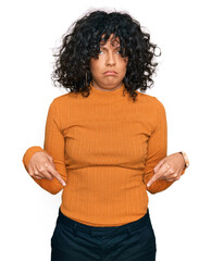 Poster - Young hispanic woman wearing casual clothes pointing down looking sad and upset, indicating direction with fingers, unhappy and depressed.