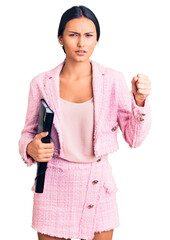 Sticker - Young beautiful latin girl wearing business clothes holding binder annoyed and frustrated shouting with anger, yelling crazy with anger and hand raised