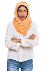 Sticker - Young brunette woman wearing traditional islamic hijab scarf skeptic and nervous, disapproving expression on face with crossed arms. negative person.