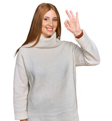 Wall Mural - Young irish woman wearing casual winter sweater smiling positive doing ok sign with hand and fingers. successful expression.